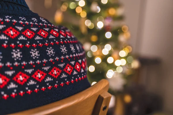 크리스마스 트리의 배경에 스웨터를 의자에 남자의 뒷모습 — 스톡 사진