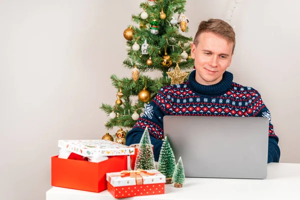 Masasında Dizüstü Bilgisayar Kullanarak Süveter Giyen Genç Bir Adam Noel — Stok fotoğraf