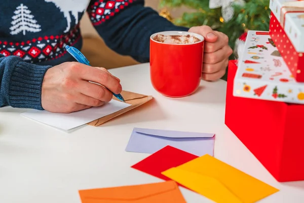 Giovane Con Maglione Firma Cartoline Scrive Lettere Vicino Albero Natale — Foto Stock