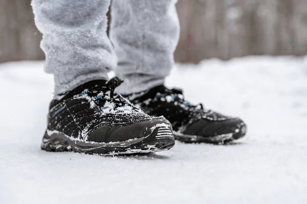 雪に覆われた森の中のスポーツシューズの男の足 — ストック写真