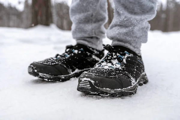 雪に覆われた森の中のスポーツシューズの男の足 — ストック写真