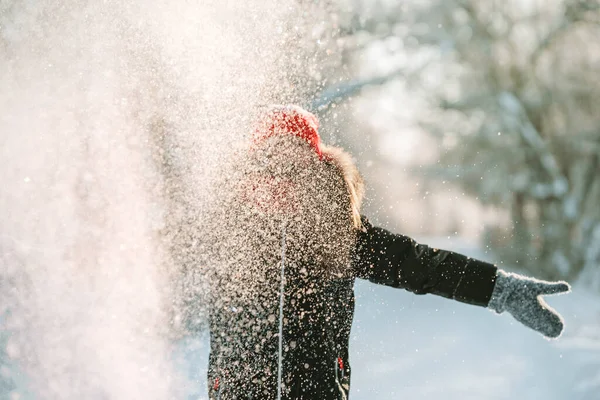 赤い帽子とスカーフの少女が雪を投げる 冬の森の雪片 — ストック写真