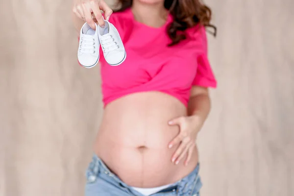 Une Femme Enceinte Tient Les Chaussures Bébé Sur Son Gros — Photo