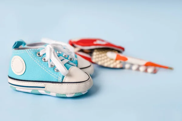 童鞋和装有温度计和蓝色背景药丸的急救箱 文字空间 儿童健康 治疗的概念 — 图库照片