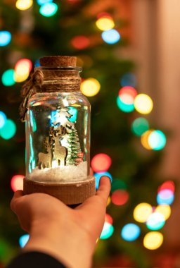 Arka planda Noel ağacı çelenkleri bulunan mutlu noel konsepti şenlik dekorasyonu hediye olarak seçici odak süslemesi