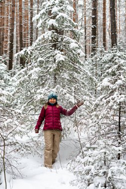 Young cheerful woman in red jacket enjoying snow falling from fir tree in winter forest, walking beauty in nature, active lifestyle, winter hiking