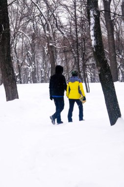 Bulutlu bir günde, kış parkında yürüyen insanlar. 