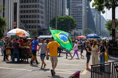 PAULO, BRAZIL - 23 Ekim 2022, güneşli Pazar, insanlar Avenida Paulista 'da günün tadını çıkarıyorlar ve Brezilya cumhurbaşkanı adaylarını desteklemek için bayraklarını taşıyorlar..