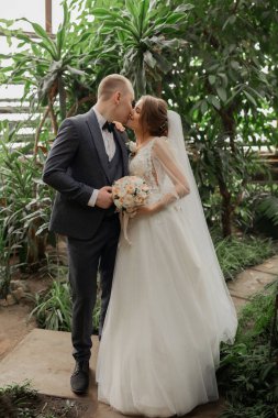 Tropikal bitkiler arasında şık gelin ve damat. Düğün günü.