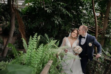 Tropikal bitkiler arasında şık gelin ve damat. Düğün günü.