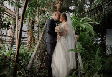 Tropikal bitkiler arasında şık gelin ve damat. Düğün günü.