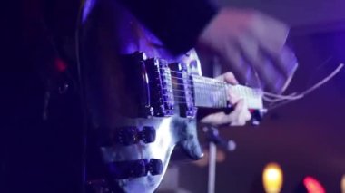 Müzisyenler konserde çalarlar. Gitaristin elleri kapalı..
