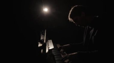 Piyanist piyano çalıyor, etrafta bir sürü mum var. Mistik atmosfer, karanlık arkaplan