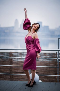 Büyük bir şehrin arka planında pembe elbiseli bir kız..