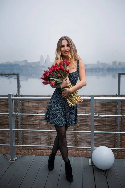 在一个大城市的背景上 一个妆容华丽 开着一束红花的女孩 — 图库照片