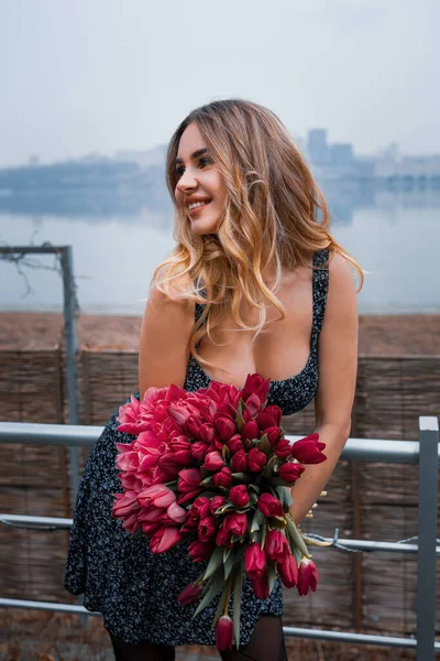 Egy Lány Fényes Sminkkel Egy Csokor Vörös Virággal Egy Nagyváros — Stock Fotó