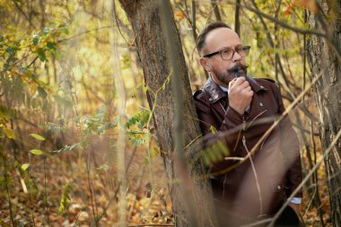 Gözlüklü şık giyinmiş bir adam, güzel bir sonbahar ormanı ve bir nehir. Yaşlı İngiliz..