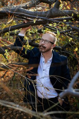 Gözlüklü şık giyinmiş bir adam, güzel bir sonbahar ormanı ve bir nehir. Yaşlı İngiliz..