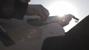 Müzisyen gün batımında bir tarlada gitar çalar. Şarap kadehli ahşap masa. Kırsal alan.