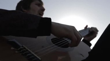 Müzisyen gün batımında bir tarlada gitar çalar. Şarap kadehli ahşap masa. Kırsal alan.