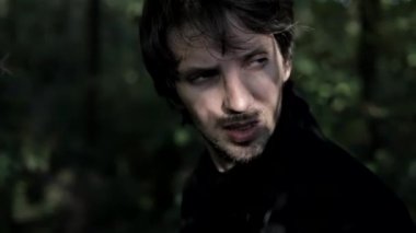 Siyahlar içinde düşünceli ve heyecanlı bir adam. Gergin ve endişeli. Depresyon ve kendini keşfetme. Orman ve açık alan