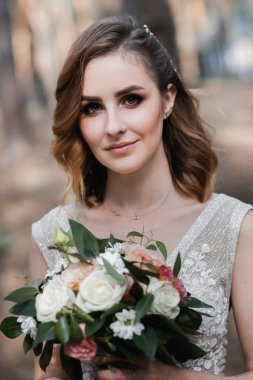 Çam ormanında güzel, tatmin olmuş bir gelin poz verir..