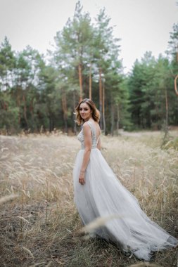 Çam ormanında güzel, tatmin olmuş bir gelin poz verir..