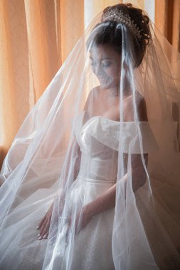 Gelin, otelde toplanıyor. Çiçek buketi ve peçe. Gün batımında uluslararası bir düğünde sevgili bir çift. Asya görünümlü güzel sofistike gelin.