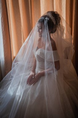 Gelin, otelde toplanıyor. Çiçek buketi ve peçe. Gün batımında uluslararası bir düğünde sevgili bir çift. Asya görünümlü güzel sofistike gelin.