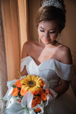 Gelin, otelde toplanıyor. Çiçek buketi ve peçe. Gün batımında uluslararası bir düğünde sevgili bir çift. Asya görünümlü güzel sofistike gelin.