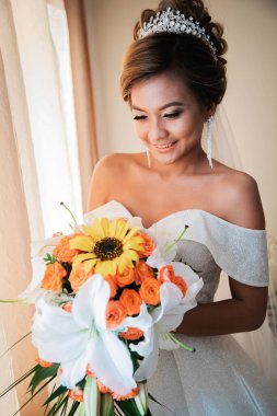 Gelin, otelde toplanıyor. Çiçek buketi ve peçe. Gün batımında uluslararası bir düğünde sevgili bir çift. Asya görünümlü güzel sofistike gelin.