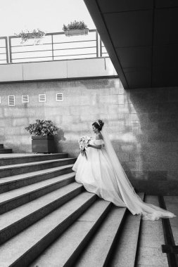 Gelinlik giymiş güzel bir Asyalı gelin gün batımında poz veriyor. Bir buket çiçek ve uzun bir peçe. Geleneksel parlak renklerde düğün dekoru. Filipin gelenekleri ve tatilleri.