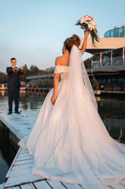 Gün batımında uluslararası bir düğünde sevgili bir çift. Asya görünümlü güzel sofistike gelin. Avrupa görünümlü şık bir damat. Karışık evlilikler.