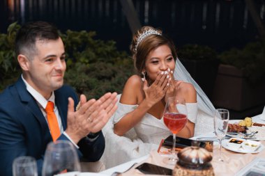 Gün batımında uluslararası bir düğünde sevgili bir çift. Asya görünümlü güzel sofistike gelin. Avrupa görünümlü şık bir damat. Karışık evlilikler.