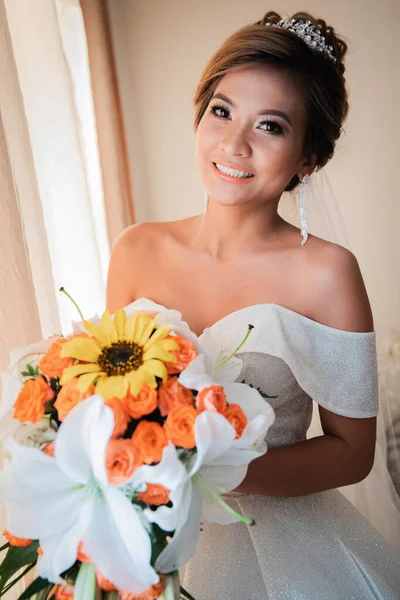 Gelin, otelde toplanıyor. Çiçek buketi ve peçe. Gün batımında uluslararası bir düğünde sevgili bir çift. Asya görünümlü güzel sofistike gelin.