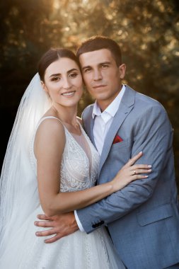 Ormanda yürüyüş için sevgili evlilik çifti. Gelinin güzel uzun bir duvağı ve siyah saçları var. Güneşli yaz günü