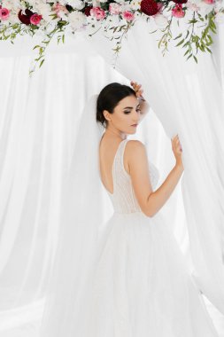 Güzel uzun bir duvağı ve düğün buketi olan mutlu bir gelin. Beyaz perdeler