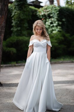 Ormanda birbirine aşık, gülümseyen bir çift el ele tutuşup sarılıyor. Güneşli bir gün, iyi bir ruh hali. Sarışın kız.