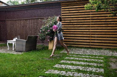 Balkonda sabahlık giymiş bir gelin. Aşık genç bir çift. Gelinin koyu renk saçları ve uzun bir peçesi var..