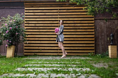 Balkonda sabahlık giymiş bir gelin. Aşık genç bir çift. Gelinin koyu renk saçları ve uzun bir peçesi var..