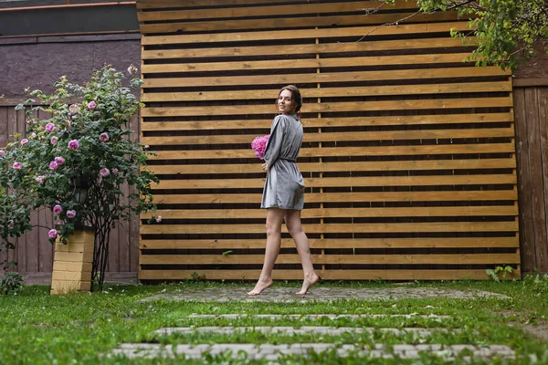 Balkonda sabahlık giymiş bir gelin. Aşık genç bir çift. Gelinin koyu renk saçları ve uzun bir peçesi var..