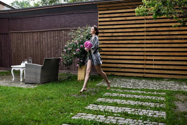 Balkonda sabahlık giymiş bir gelin. Aşık genç bir çift. Gelinin koyu renk saçları ve uzun bir peçesi var..