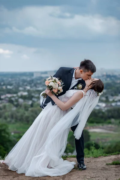 新娘和新郎在乌云密布的天空中 美丽的面纱在风中飘扬 — 图库照片