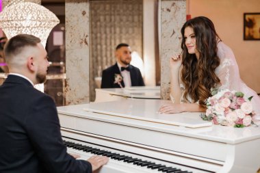 Beyaz bir piyanonun arkasında papyonlu şık bir damat..