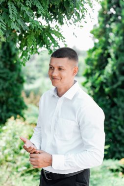 Utanmış gülen damat. Düğün kıyafetleri içinde çok kültürlü mutlu bir çift. Göllü botanik bahçesi.