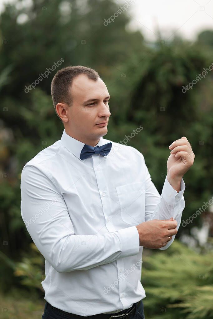 Positive charming groom with a bow tie and in a white shirt. Portrait of a man.