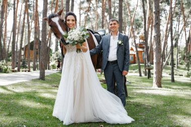 Genç ve evli bir çift ormanda yürüyüşe çıkmış kahverengi bir atla..