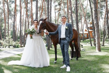 Genç ve evli bir çift ormanda yürüyüşe çıkmış kahverengi bir atla..