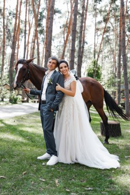 Genç ve evli bir çift ormanda yürüyüşe çıkmış kahverengi bir atla..