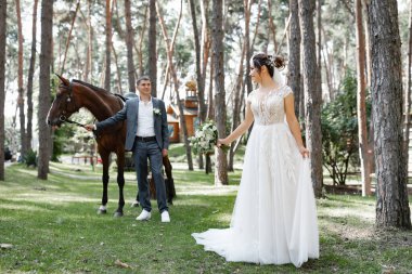 Genç ve evli bir çift ormanda yürüyüşe çıkmış kahverengi bir atla..